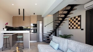 A modern kitchen with a central island, stainless steel appliances, and a staircase leading to an upper level. - VillAgioi II - 2 BR Villa, Pool & BBQ, Walk to Beach (Chania)