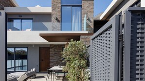 A modern building with a stone facade, a balcony with seating, and a dining area with a table and chairs. - VillAgioi II - 2 BR Villa, Pool & BBQ, Walk to Beach (Chania)
