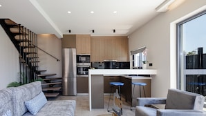 A modern kitchen with a central island, stainless steel appliances, and a bar stool. - VillAgioi IIΙ - Stylish Pool Villa, 450m to Sandy Beach (Chania)