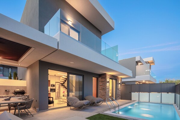 A modern house with a swimming pool, outdoor seating, and a staircase leading to an upper level. - VillaSaints - Two Pool villas, Walk to Beach, BBQ (Chania)