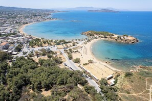 An aerial view of a coastal town with a beach, clear blue waters, and a mix of residential and commercial buildings. - VillaSaints - Two Pool villas, Walk to Beach, BBQ (Chania)
