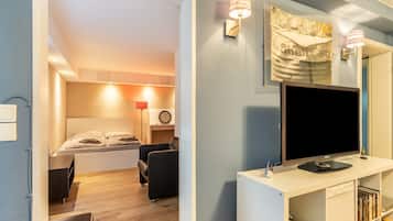 Ein modernes Zimmer mit Bett, Schreibtisch, Fernseher und Bücherregal.