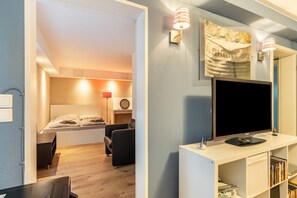 Ein modernes Zimmer mit Bett, Schreibtisch, Fernseher und Bücherregal.