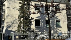 Rakennus, jonka yläosa on tehty puusta ja alaosa on maalattu valkoiseksi. Rakennuksen ympärillä on puita ja maaperä on lumen peitossa.