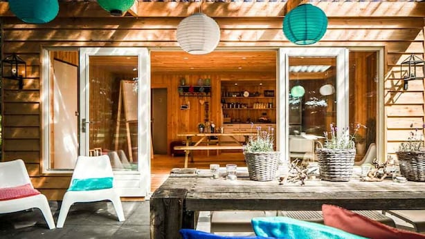 Una terraza de madera al aire libre con una mesa, sillas y plantas en macetas.