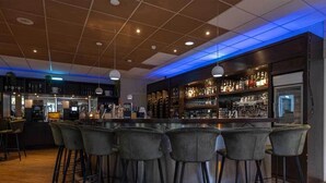 A bar area with a round bar and six stools, a counter with a cash register, and shelves with bottles and glasses.