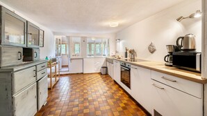 Eine Küche mit Schachbrettboden, weißen Schränken, einem Herd und einer Kaffeemaschine.