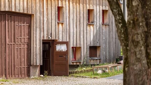 Ein rustikales Holzhaus mit einer großen Holztür, einer kleineren Tür und zwei Fenstern.
