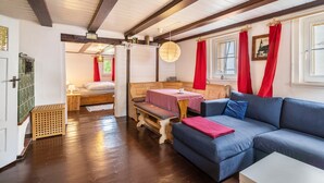 Ein gemütliches Zimmer mit einer Holzbank, einem blauen Sofa und einem Tisch mit einer rot-weißen karierten Tischdecke.