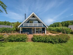 Une maison moderne dotée d’un toit en pente, d’un patio couvert et offrant une vue sur la verdure environnante.