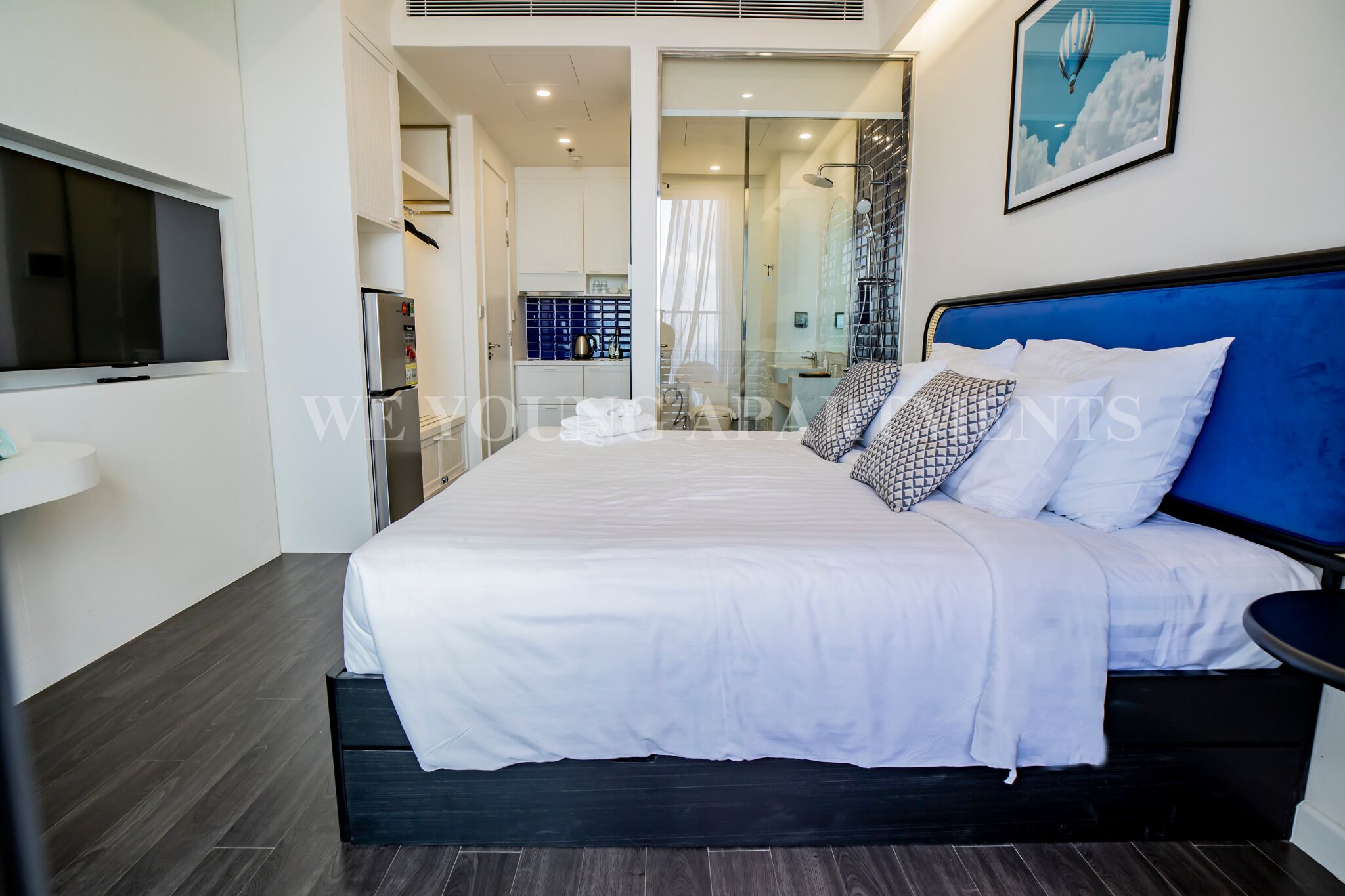 A modern bedroom with a large bed, a TV, and a bathroom visible through a glass door.