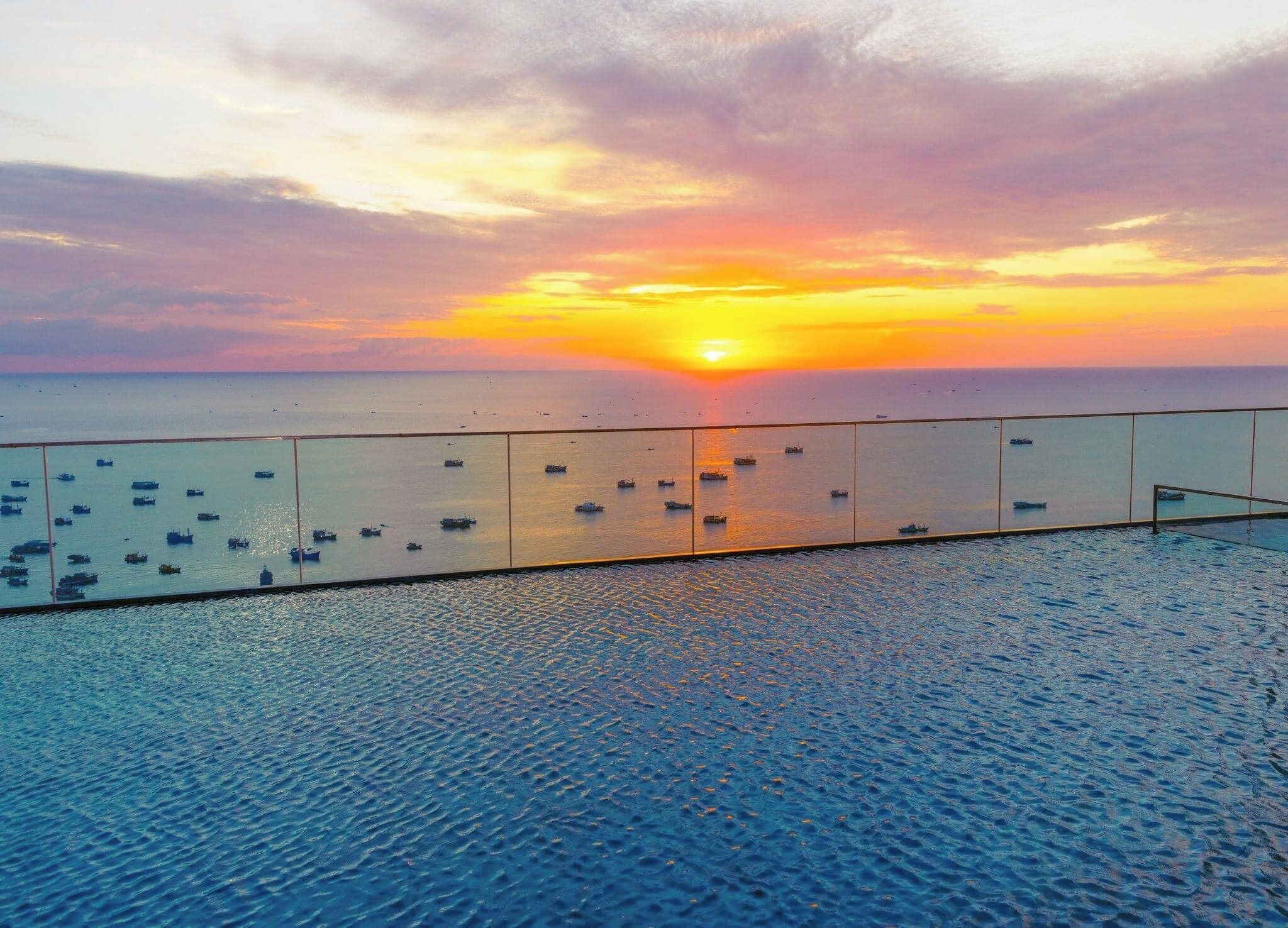 Ein Sonnenuntergangsblick vom Balkon mit Geländer auf das Meer, mit mehreren Booten.