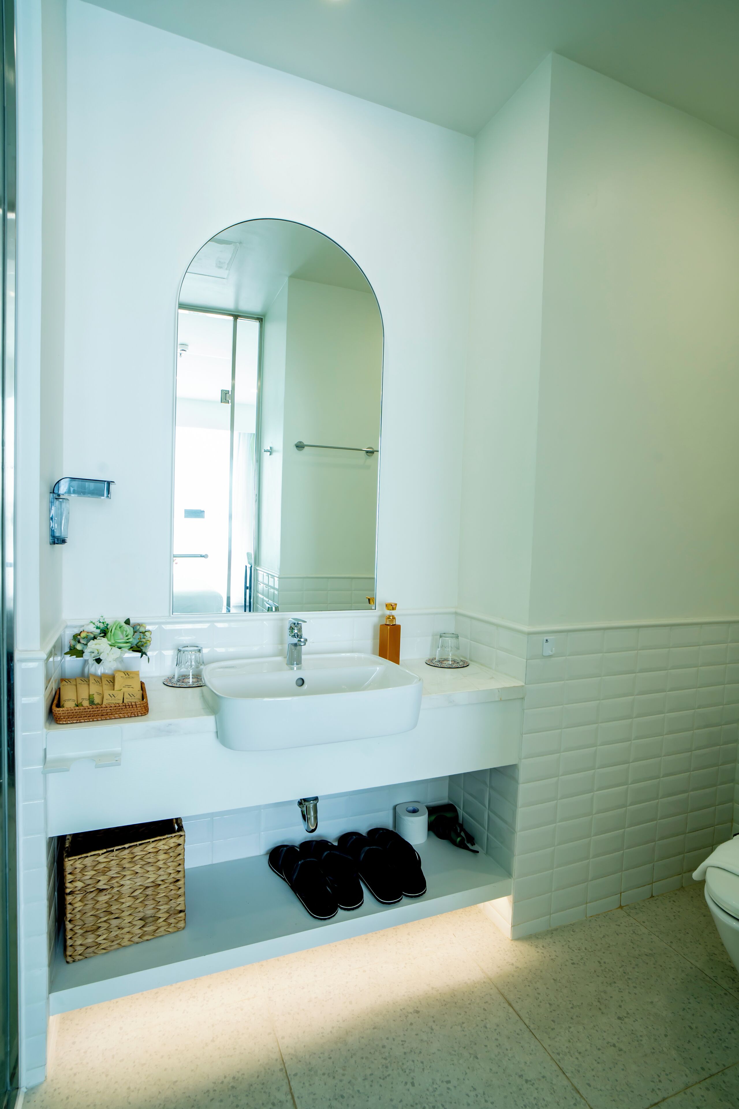 A modern bathroom with a white sink, mirror, and tiled walls.