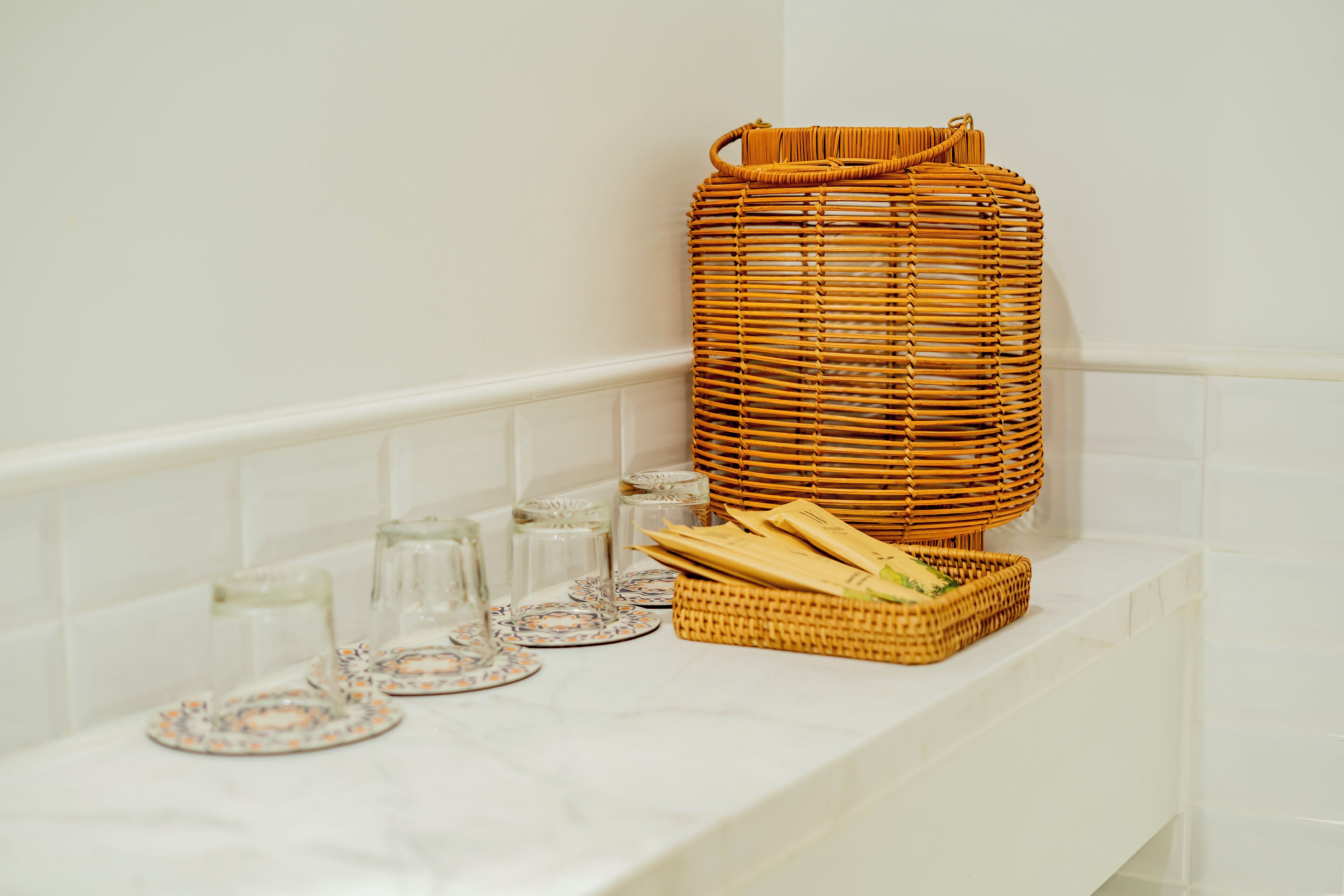 A bathroom with a white bathtub, a wicker basket, and a tray with plates and glasses.
