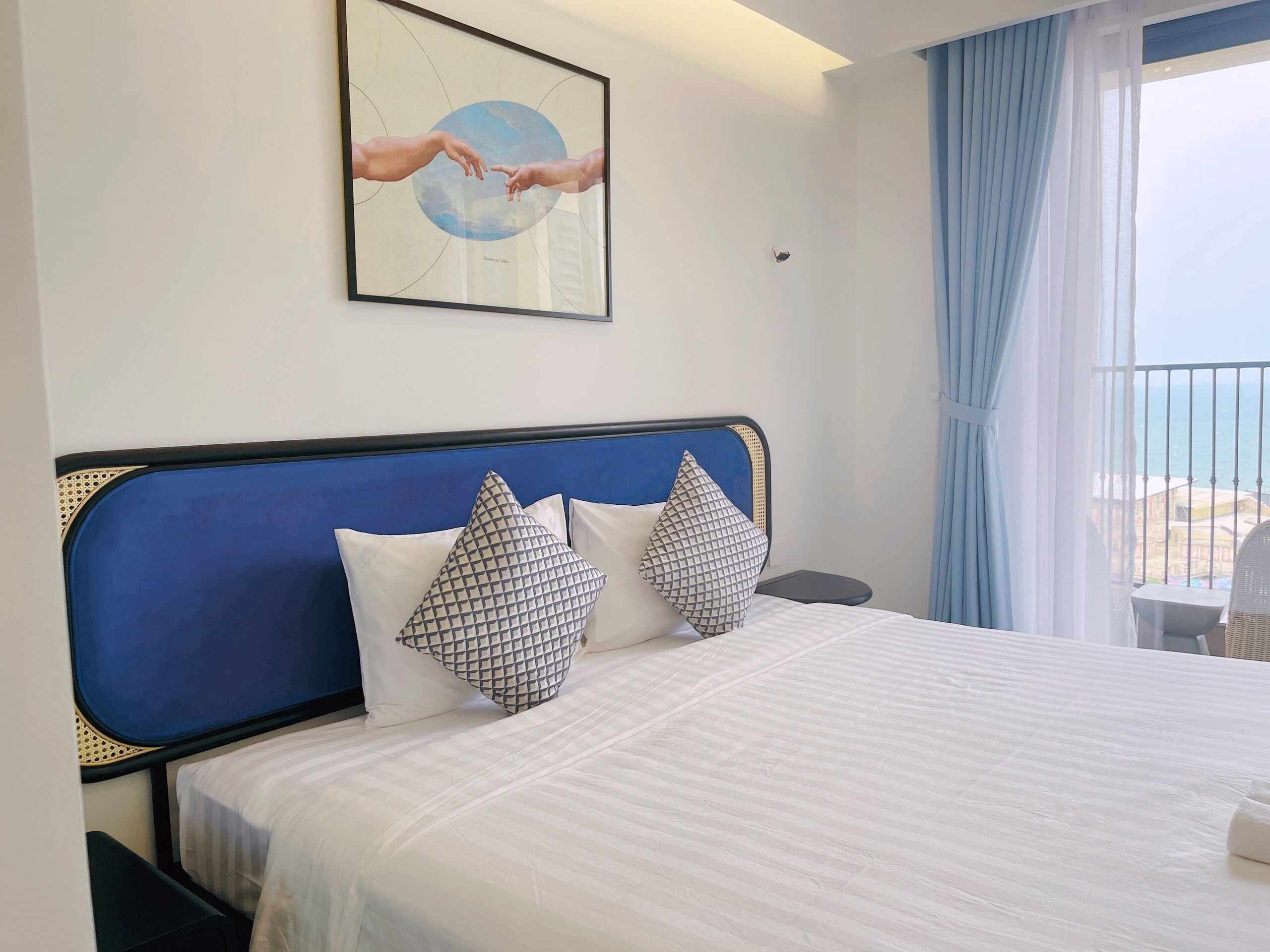 Habitación de hotel con cama, una obra de arte enmarco y vista al mar.