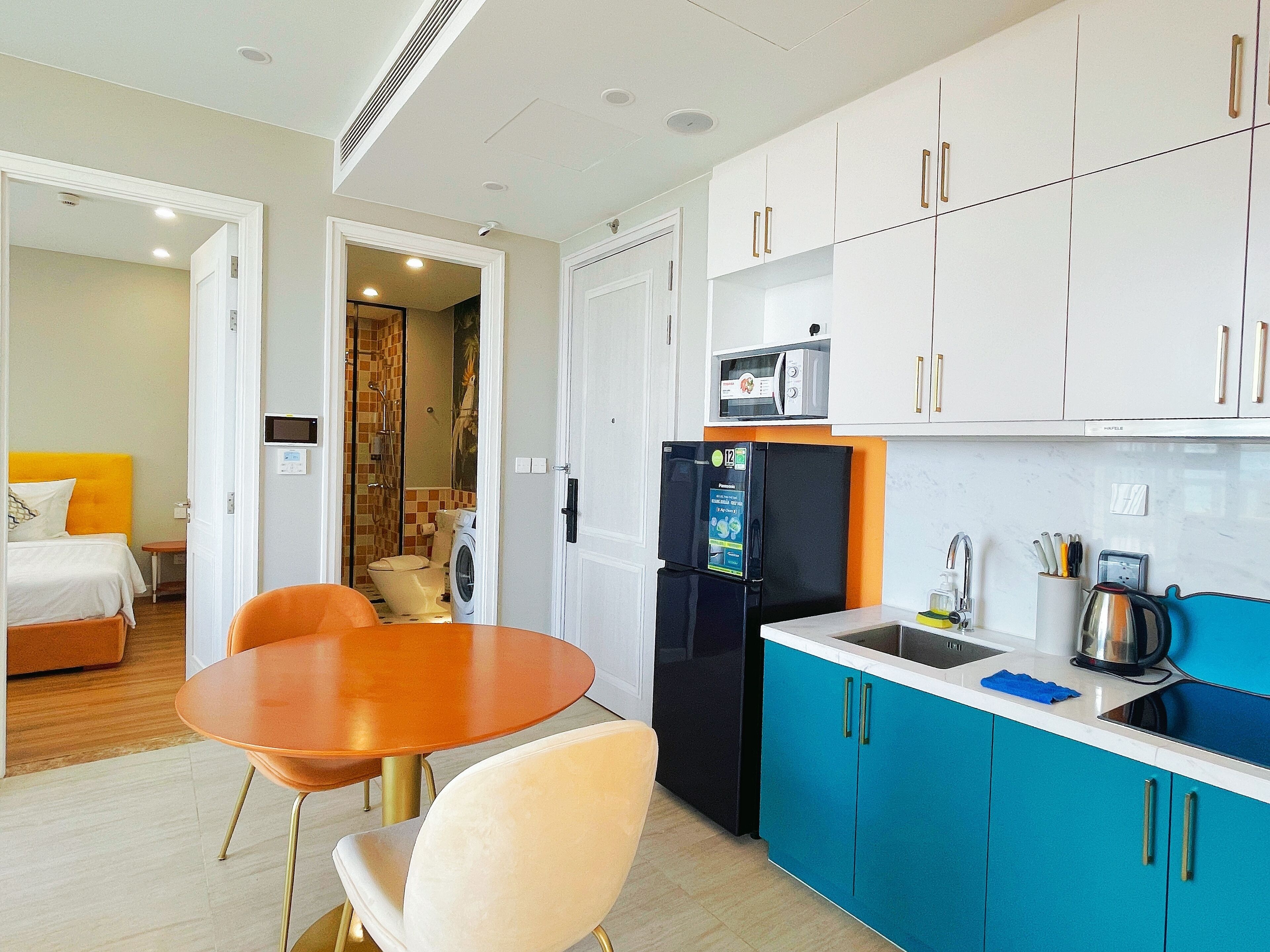 A compact hotel room with a bed, a dining table, and a kitchenette.