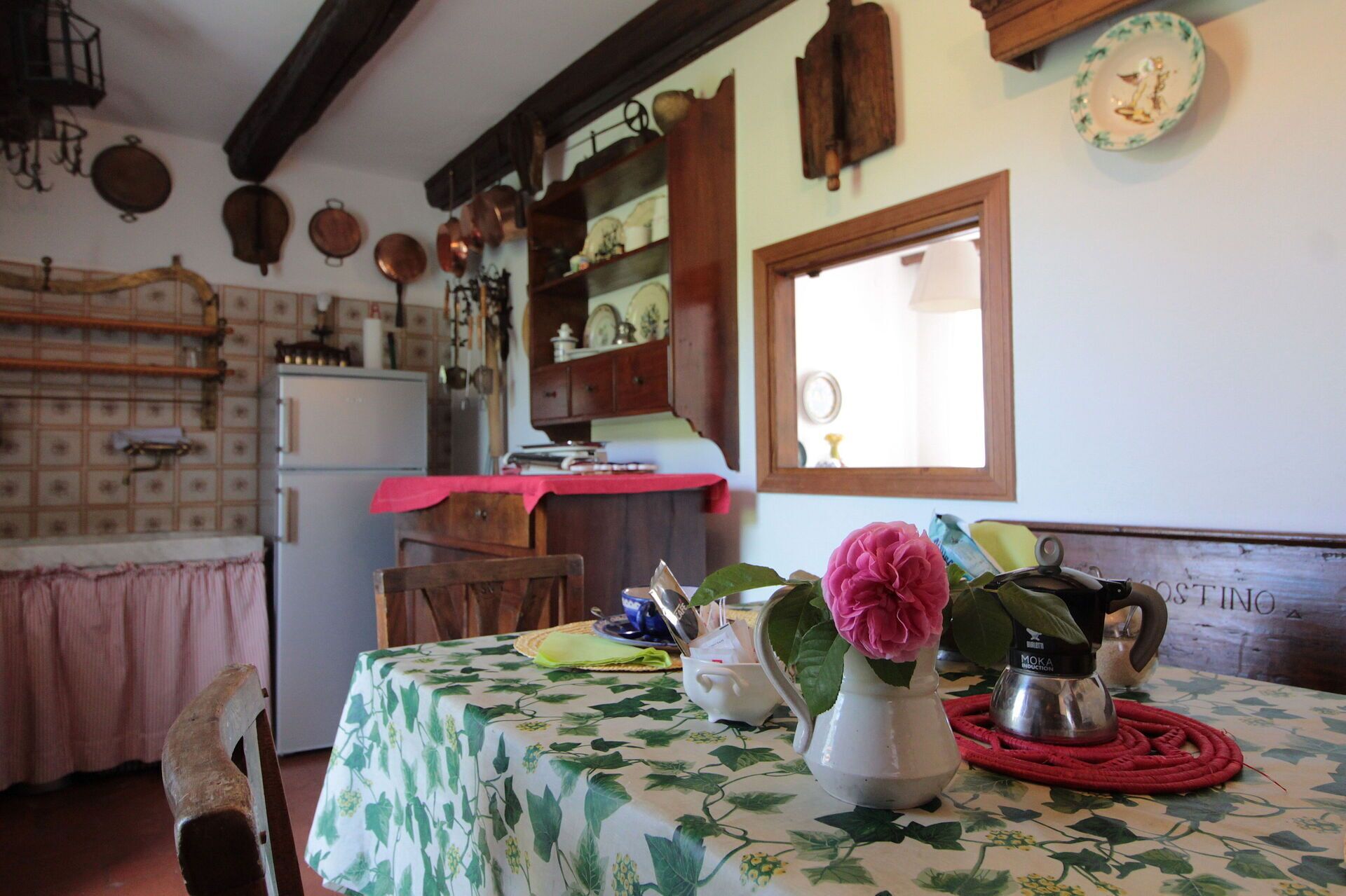 Une cuisine traditionnelle avec une table mise pour le repas, un vase rempli de fleurs et divers ustensiles de cuisine.