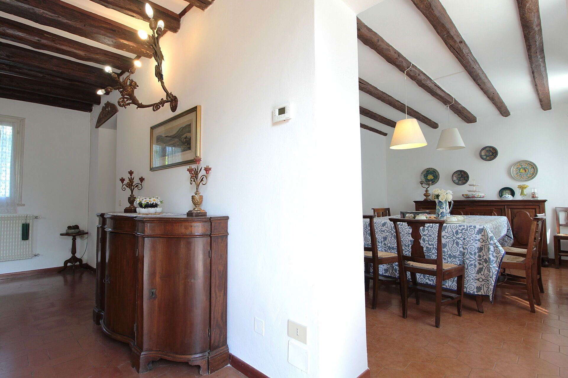 A dining area with a table set for two, wooden chairs, and a chandelier.