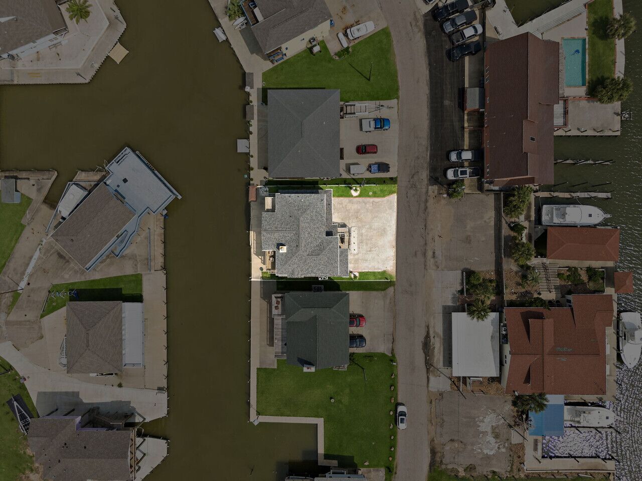 Vue aérienne d’un quartier résidentiel avec des maisons, un quai et un petit port de plaisance.