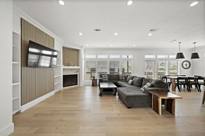 A spacious living room with a large sectional sofa, a fireplace, and a dining area with a round table and chairs. - Fisherman’s Dream: Canal Front Home & Views (Surfside)