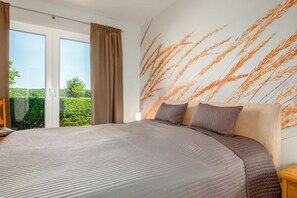 Una camera da letto con un grande letto, una porta scorrevole in vetro su un giardino e un pannello decorato con spighe di grano.