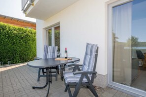 Un patio con tavolo e sedie, una bottiglia di vino e vista attraverso una porta vetrata.