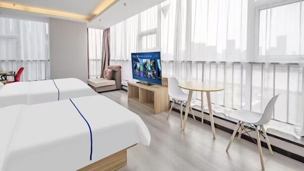 A hotel room with two beds, a TV, a small table, and a chair.