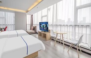 Een hotelkamer met twee bedden, een televisie, een klein tafeltje en een stoel.