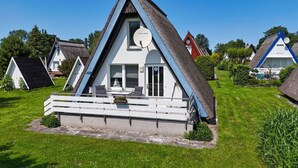Una casa triangular con una antena parabólica, un balcón y el número 70 en la puerta.