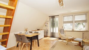 Una habitación acogedora y bien iluminada con una mesa de madera, sillas, un radiador y una ventana con cortinas.
