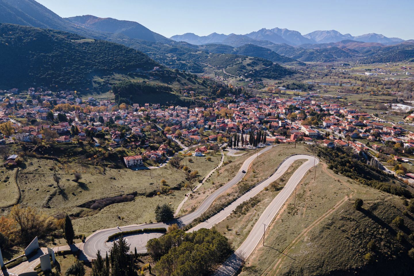 Une ville nichée dans une vallée, entourée de routes sinueuses et dominée par un paysage montagneux.