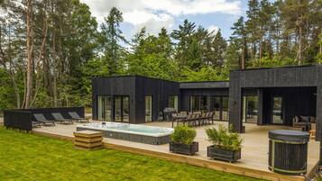 Un espace de vie extérieur moderne doté d’un jacuzzi, de sièges et d’une terrasse.