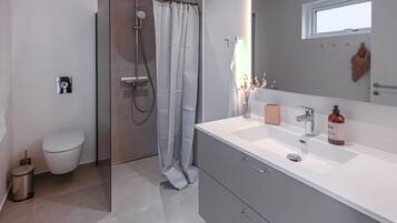 Une salle de bain moderne équipée d’une douche, de toilettes et d’un meuble-lavabo avec un miroir.