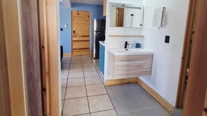 A narrow hallway with a kitchen area featuring a white countertop, a sink, and a mirror. - MARINA AZUL Charming 2-bedroom apartment in beautiful La Paz with WiFi, AC (La Paz BCS)