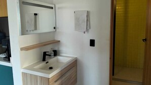 A modern bathroom with a sink, mirror, and towel rack. - MARINA AZUL Charming 2-bedroom apartment in beautiful La Paz with WiFi, AC (La Paz BCS)