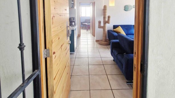A hallway with a wooden door, a blue sofa, and a fish decoration on the wall. - MARINA AZUL Charming 2-bedroom apartment in beautiful La Paz with WiFi, AC (La Paz BCS)