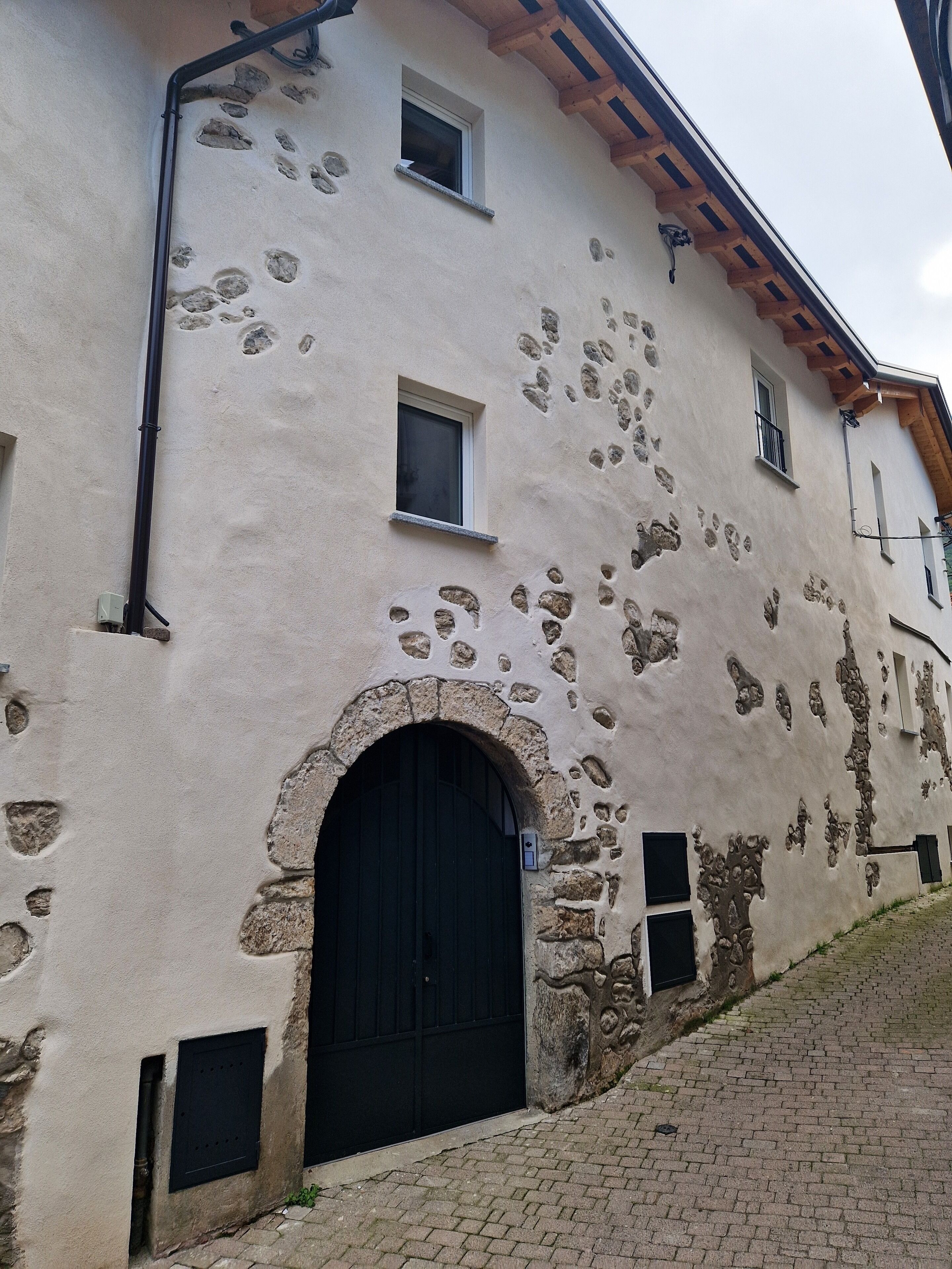 A building with a stone facade, a black arched entrance, and small windows.