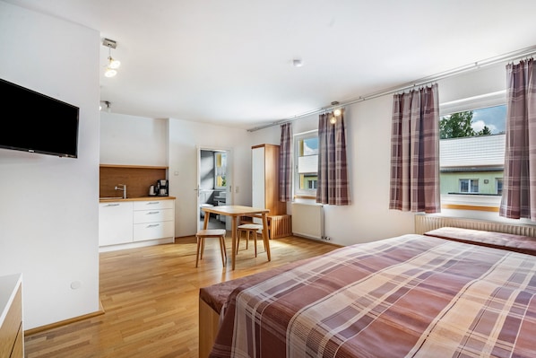 A bedroom with a bed, a desk, and a window with curtains.