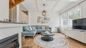 Una sala de estar moderna con un sofá modular, una mesa de centro redonda, una chimenea y un televisor.