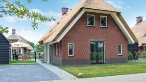 Ein traditionelles Backsteingebäude mit einem strohgedeckten Dach und einer großen Glasdoor.