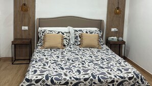 A bedroom with a large bed, two bedside tables, a wooden slat wall, and recessed ceiling lights.