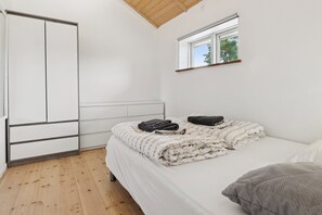 Ein Schlafzimmer mit Bett, Fenster, Kleiderschrank und Heizkörper.