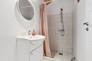 Ein Badezimmer mit Dusche, Waschbecken und Spiegel.