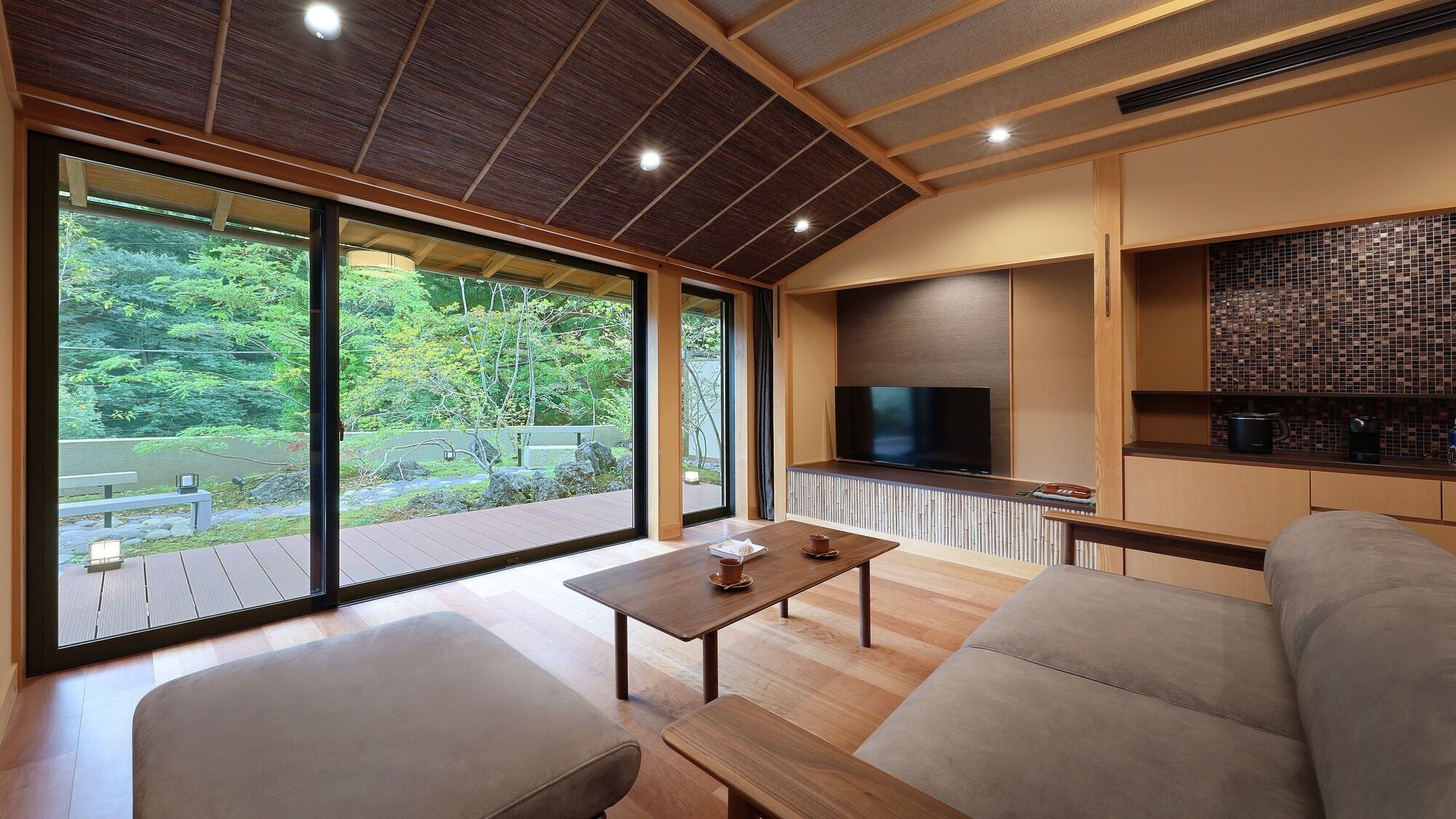 A modern interior with a wooden floor, a sofa, a table, and a TV mounted on a wall.
