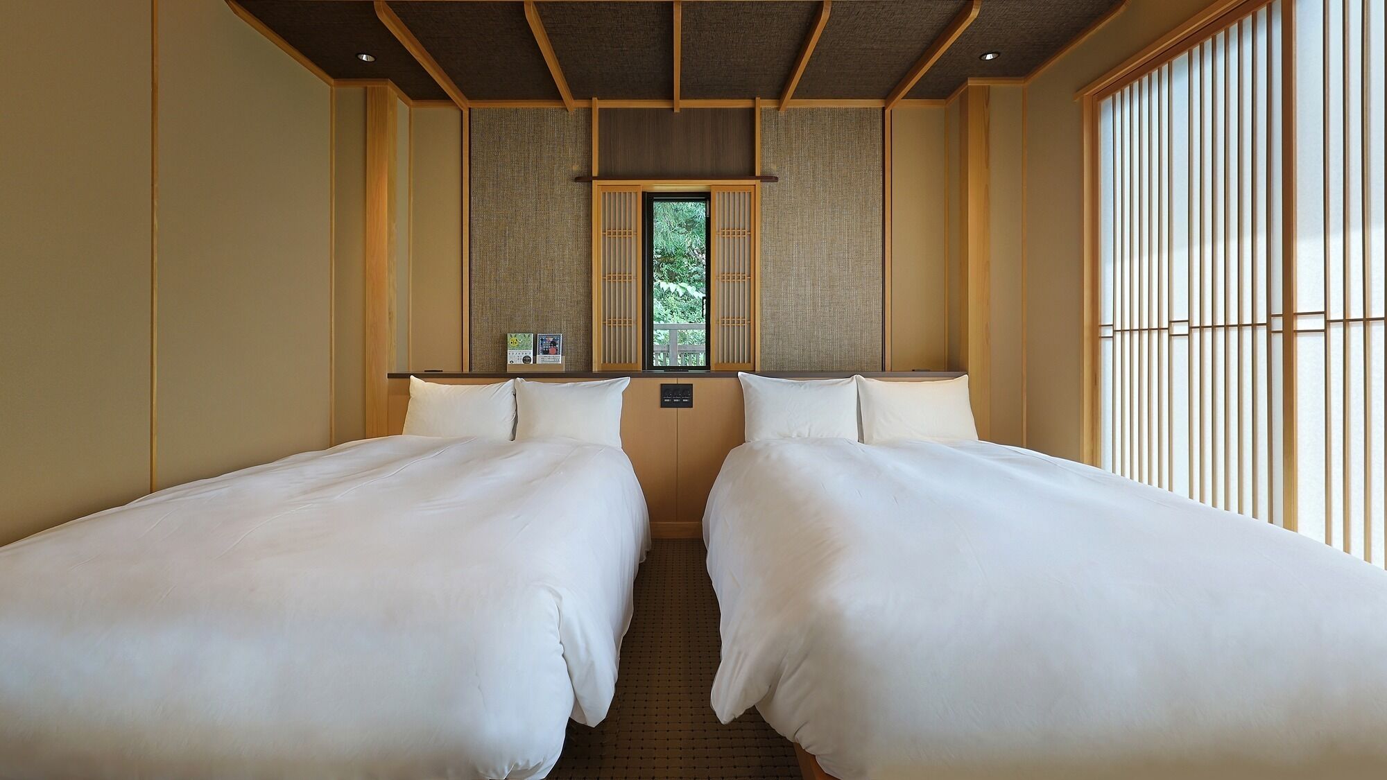 Habitación de hotel con dos camas individuales, una ventana con vista a follaje y un puertas correderas de estilo japonés tradicional.