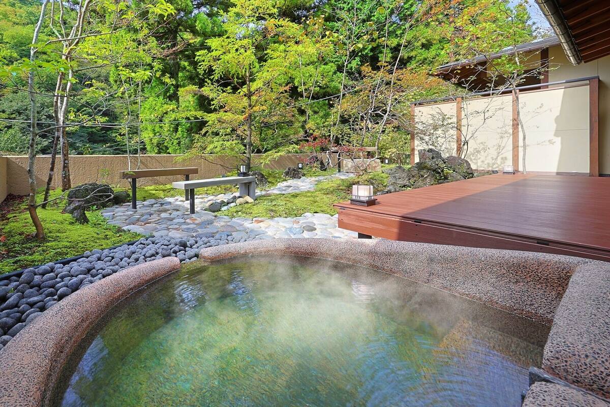 Ein traditioneller japanischer Garten mit Thermalbad, Steinwegen und hölzernen Bänken.