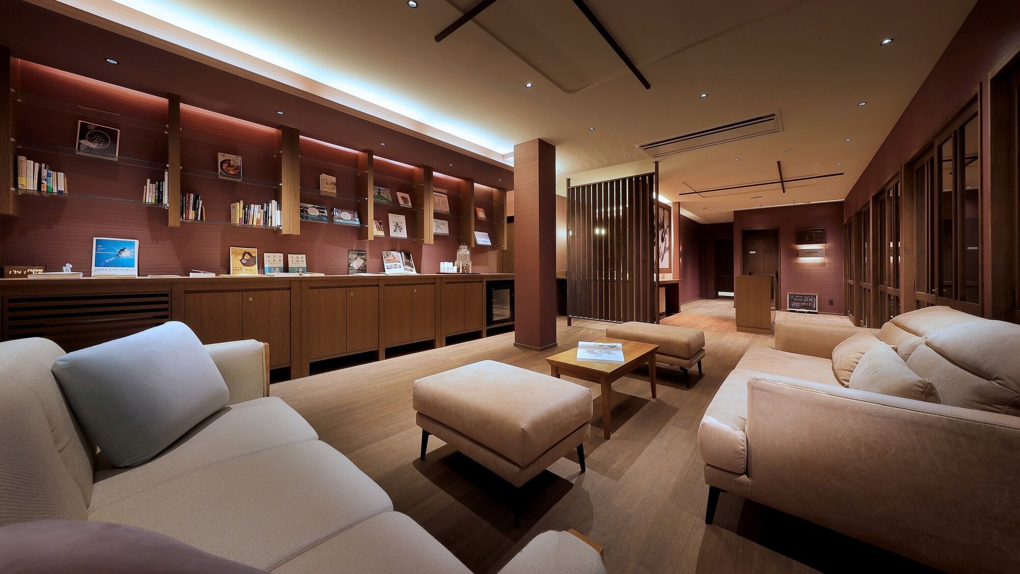 A modern hotel lobby with a reception desk, seating area, and bookshelves.