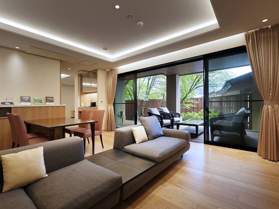 A modern living room with a sofa, a dining table, and a kitchen area.