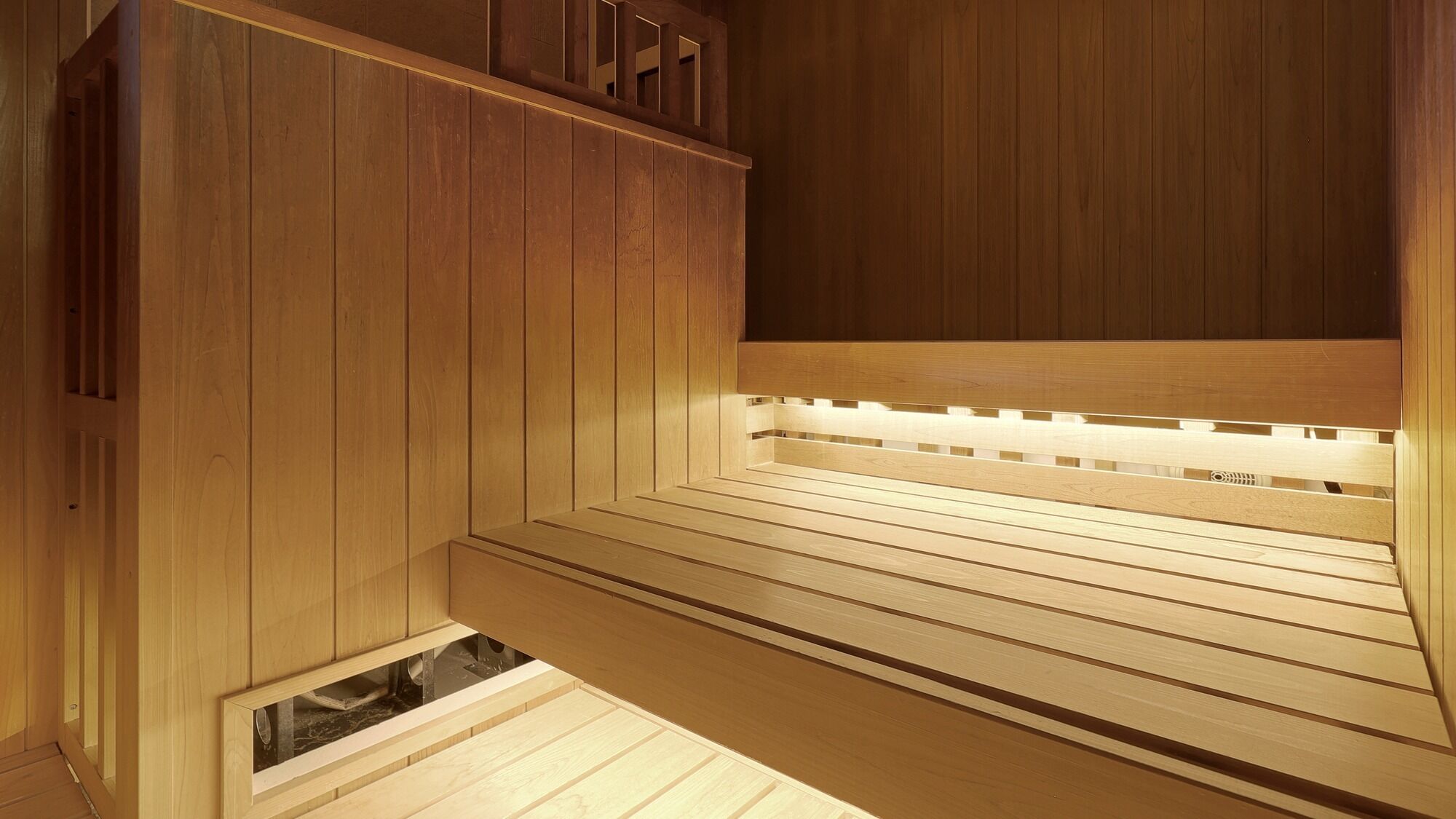 Un sauna en bois avec des bancs et une banquette.