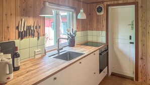 Une cuisine avec des meubles de rangement en bois, un évier et une fenêtre.